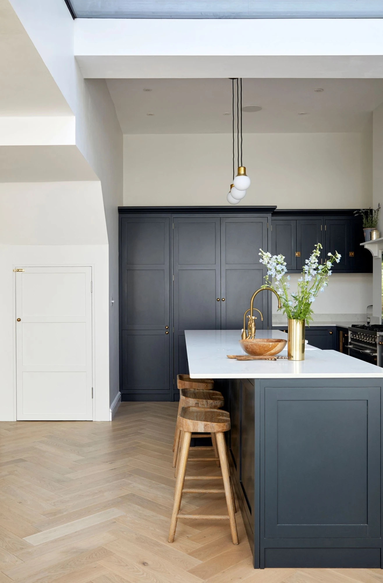 A stylish central island anchors the Heathwood Gardens kitchen, providing an additional workspace and ample seating for gatherings. The island's sleek design and matching dark blue panelling complement the surrounding cabinetry, creating a cohesive and stylish ensemble.