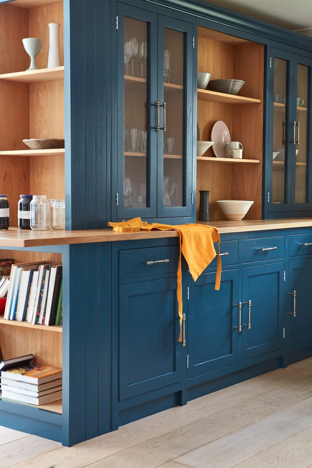 The Cley kitchen offers ample space for culinary adventures, with generous storage and a spacious layout. The use of blue base cabinets and grain-visible paint finish on the tall Shaker units showcases the natural beauty of the wood..