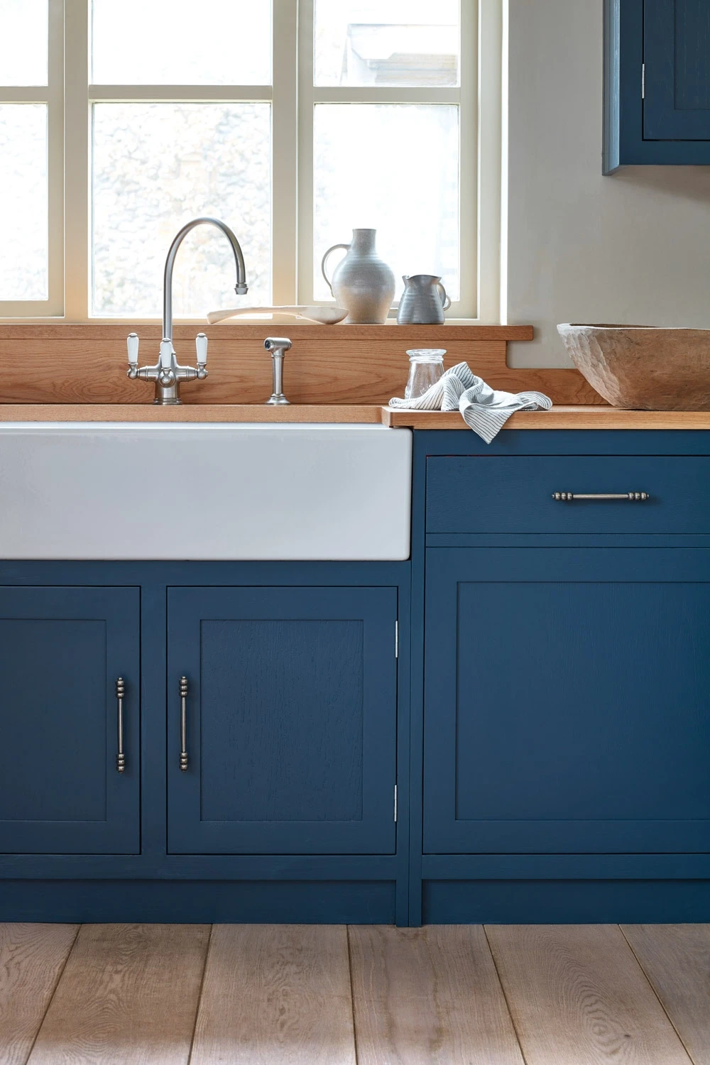 The kitchen's design is both functional and aesthetically pleasing, making it a perfect place to prepare and enjoy meals.The contrast between the blue cabinets and the wood countertop adds a touch of elegance