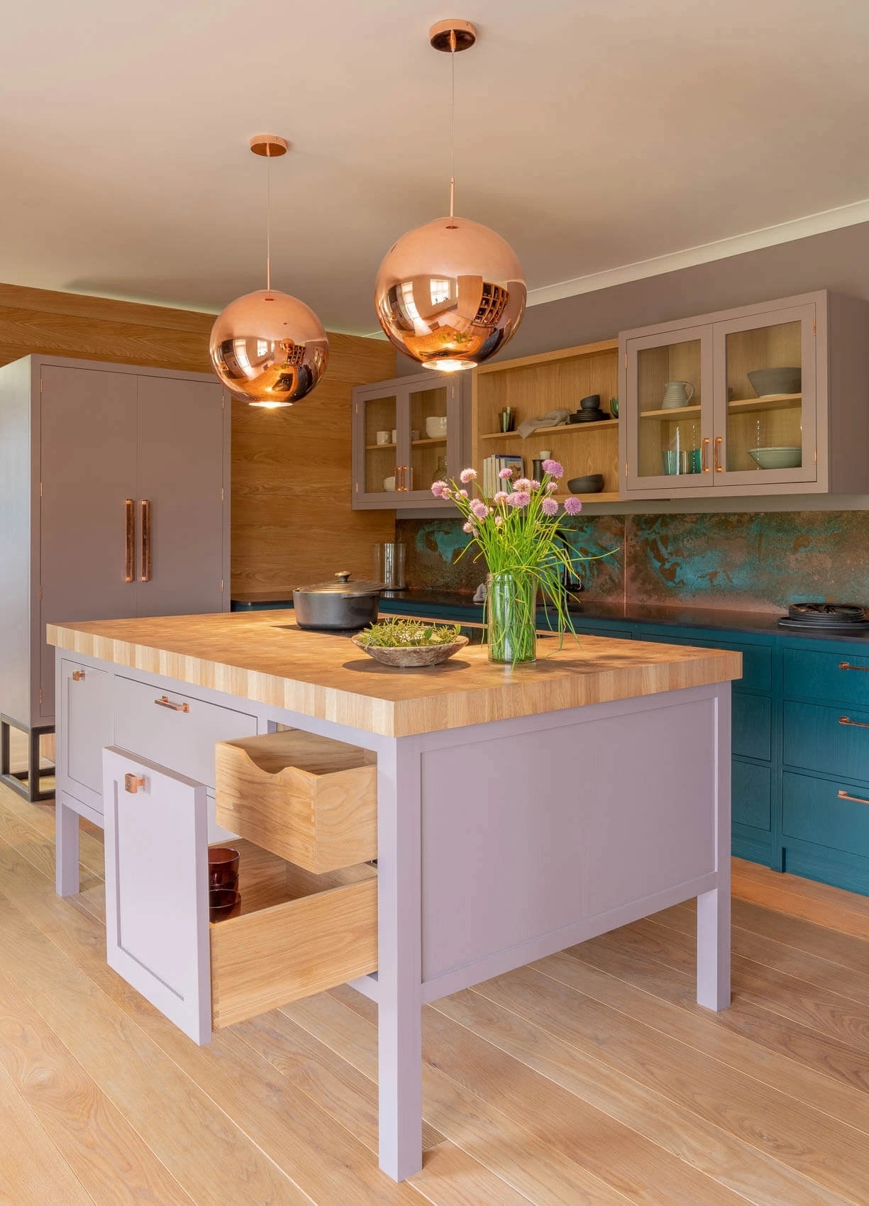 Step into a culinary haven, where a blend of green, dusky pink paintwork, and oak cabinetry exudes elegance and warmth. The central island anchors the kitchen, providing an additional workspace and seating area.