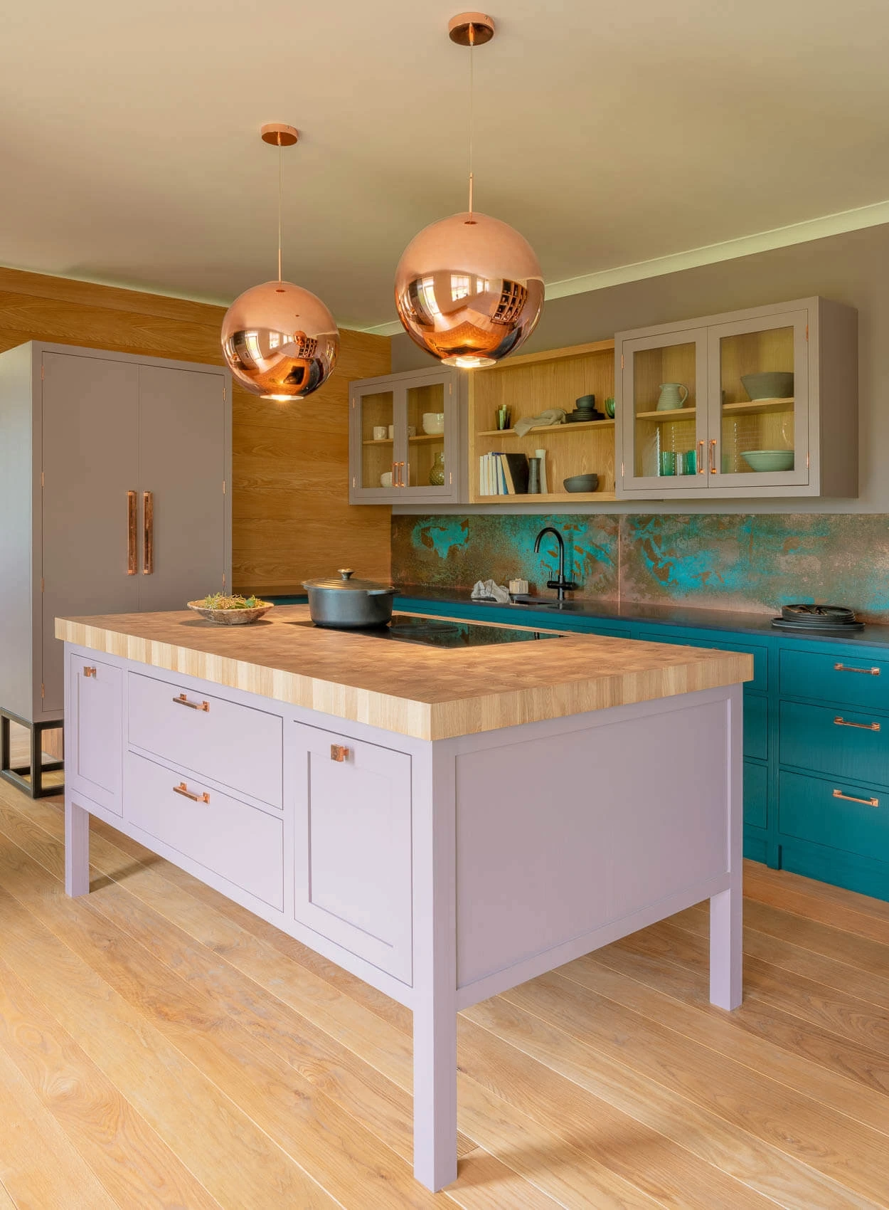 Step into a culinary haven, where a blend of green, dusky pink paintwork, and oak cabinetry exudes elegance and warmth. The central island anchors the kitchen, providing an additional workspace and seating area.