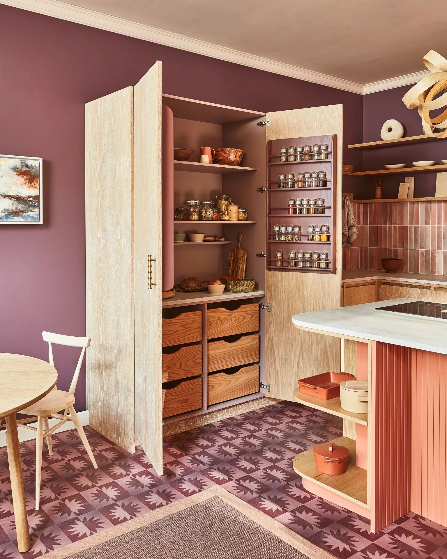 A mesmerizing vista of the kitchen's stunning larder, a hidden treasure trove for storing and displaying culinary delights. The larder's opulent interior, adorned in rich 'Wild Heather' color and contrasting spice racks, exudes elegance and functionality.