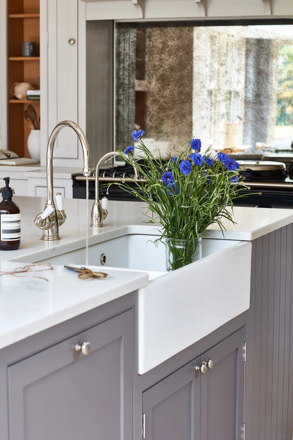 Delightful scene within the Norfolk Vicarage kitchen, featuring a collection of oversized limestone slabs, adding a touch of rustic charm and natural beauty to the space. The oversized limestone slabs in this kitchen add a touch of rustic charm and natural beauty to the space. They serve as a backdrop for the island and provide a spacious and inviting dining area.