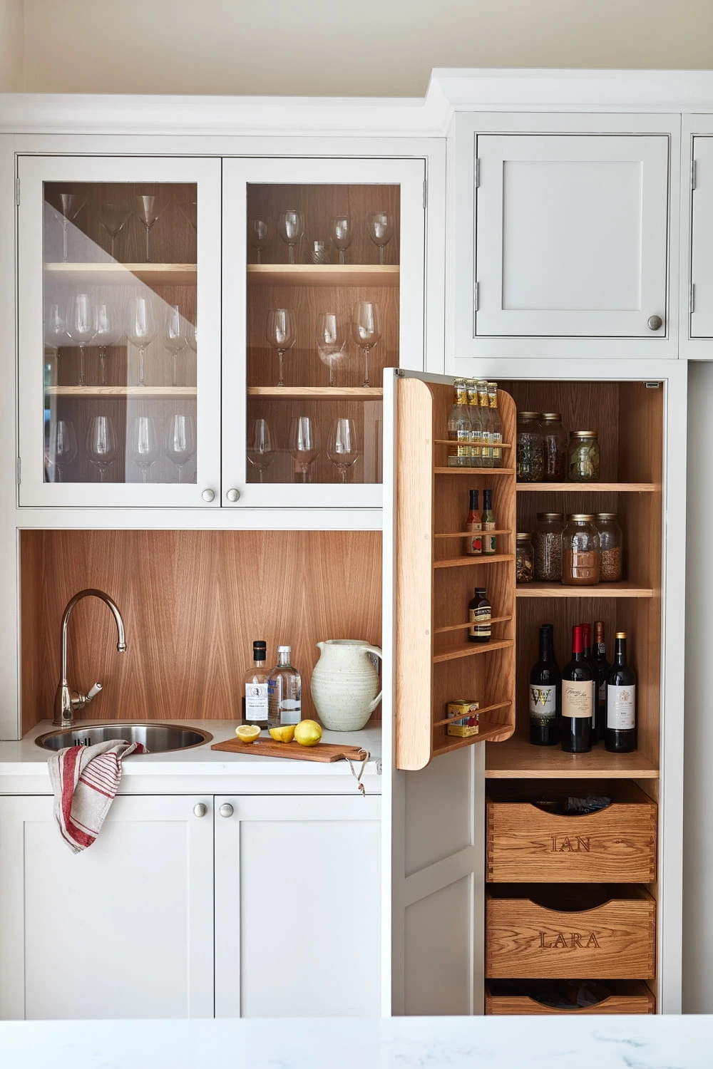 Delving into the details, this image showcases the Norfolk Vicarage kitchen's bespoke cocktail corner, nestled within the island. The corner features eye-level glass cabinets, and engraved oak drawer boxes, creating a sophisticated and functional space for bartending and entertaining.