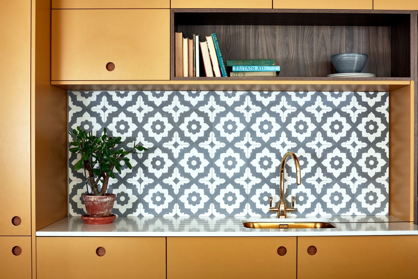 An intricately tiled splashback draws the eye and adds a unique artistic touch, complementing the minimalist design.