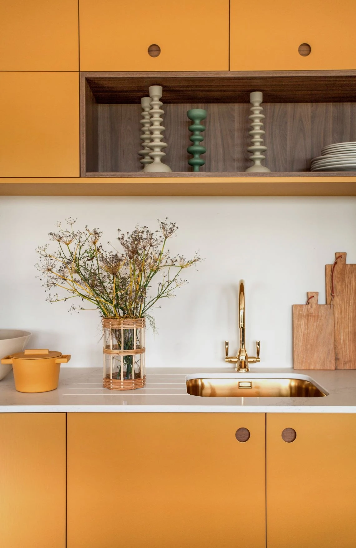 Rich ochre tones and brass fixtures gleam under natural light, adding warmth and sophistication to the sleek contemporary cabinets.