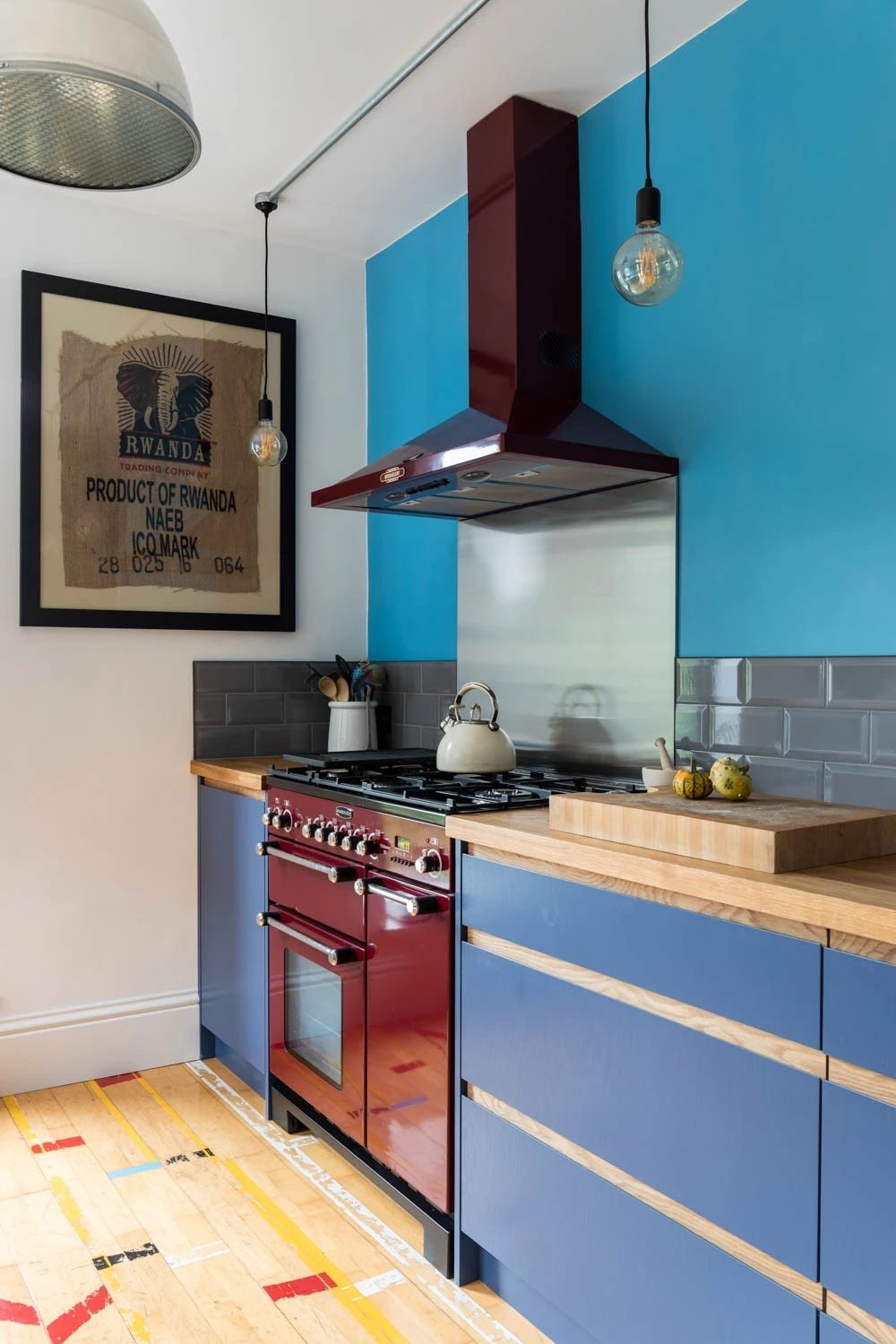 Fiery red Rangemaster takes center stage, commanding attention over sleek blue J-groove cabinetry doors, creating a bold and modern kitchen masterpiece.