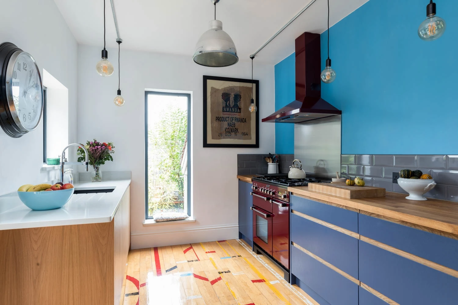  A symphony of vibrant blue and pristine white defines this contemporary kitchen, with a majestic window offering a glimpse of nature's serenity, ideal for inspiring culinary creativity.