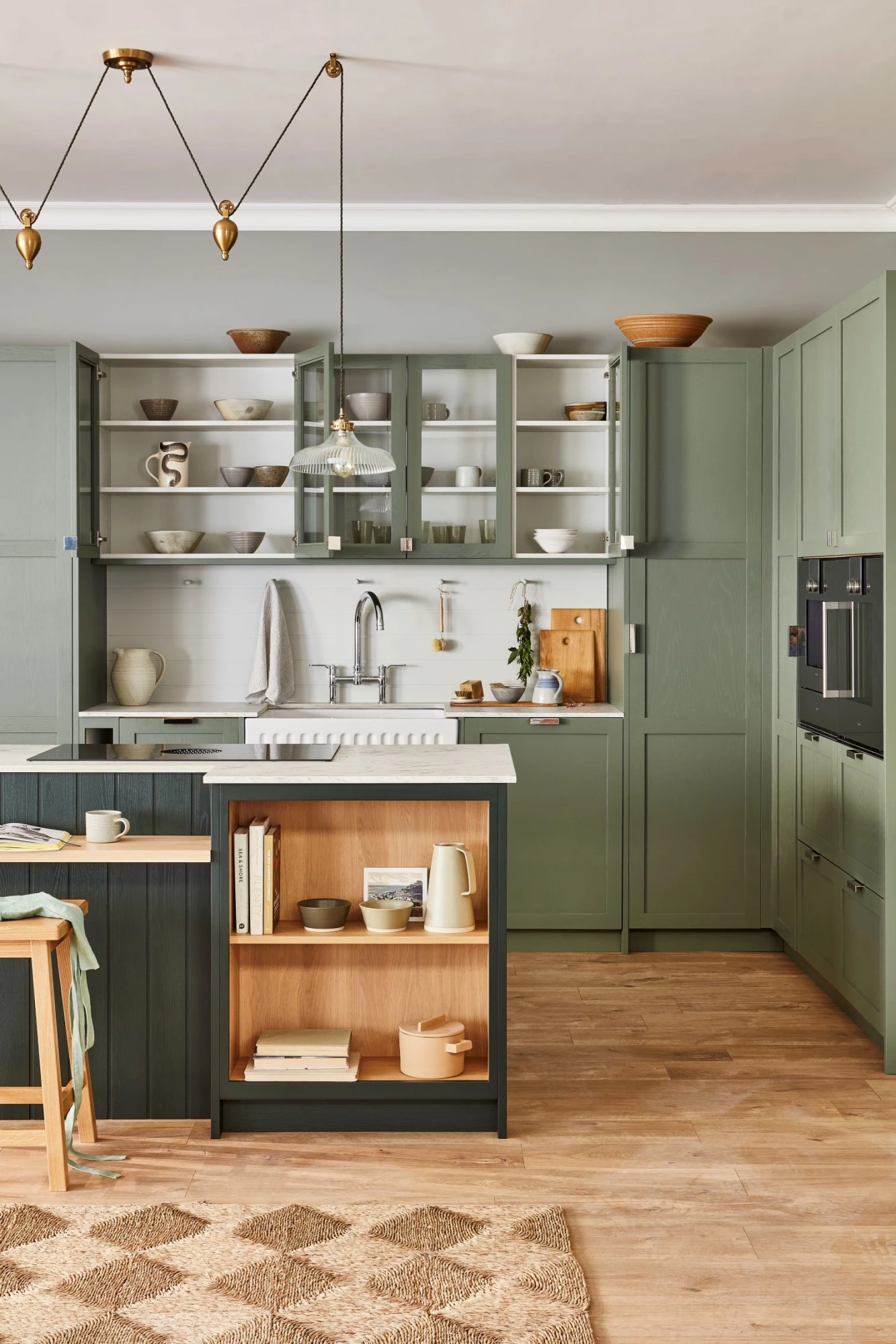 A closer look at the captivating green cabinetry, adorned with intricate shaker detailing, creating a harmonious blend of classic charm and modern sensibilities. The glazed cabinetry showcases a collection of culinary treasures, adding a touch of personality and warmth to the kitchen's ambiance