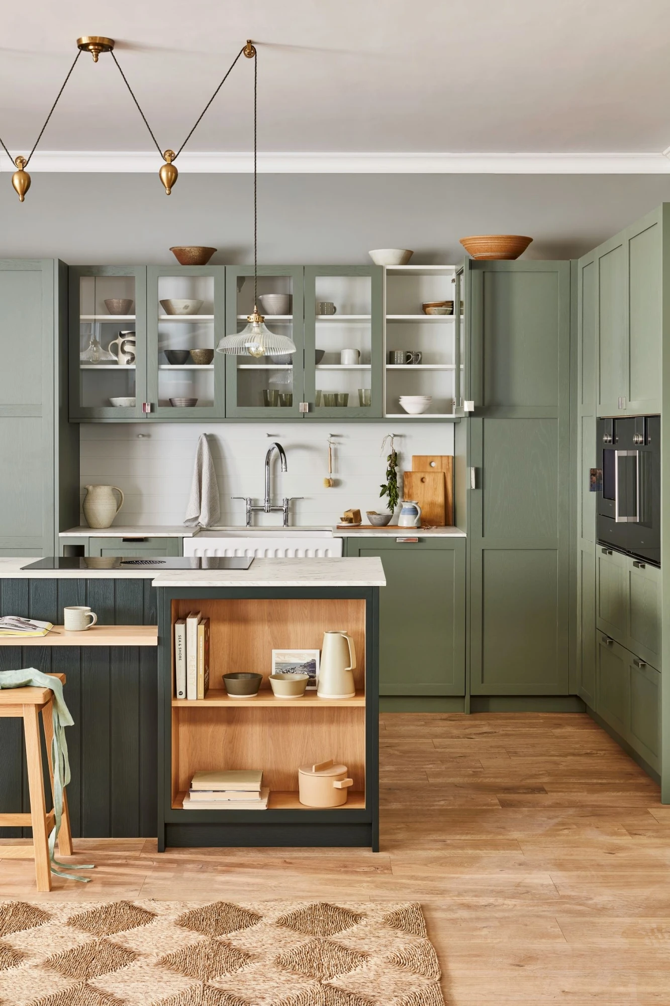 A closer look at the captivating green cabinetry, adorned with intricate shaker detailing, creating a harmonious blend of classic charm and modern sensibilities. The glazed cabinetry showcases a collection of culinary treasures, adding a touch of personality and warmth to the kitchen's ambiance