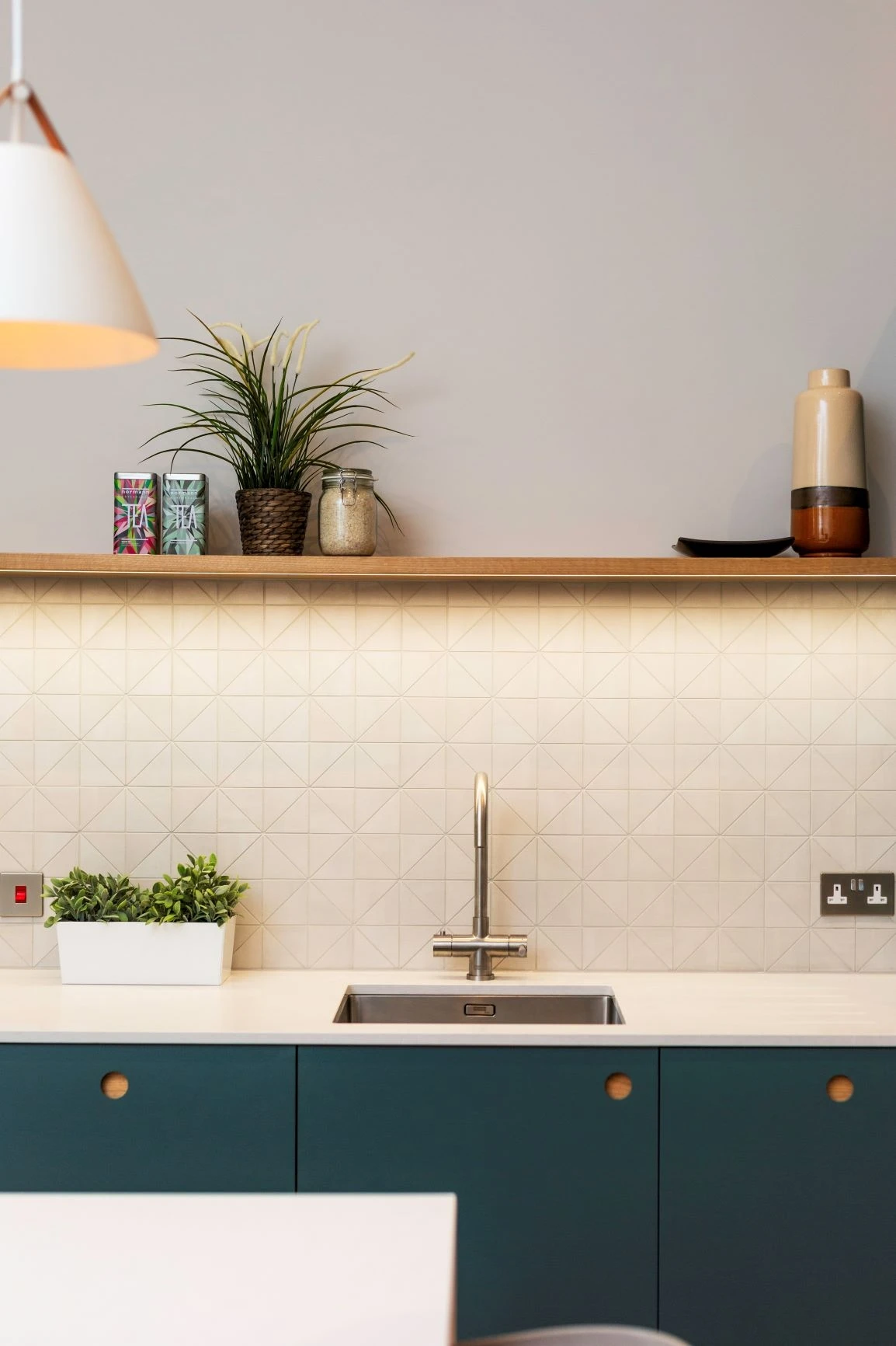 This elegant kitchen features a combination of green ladbroke style doors, a white worktop, and a tiled splashback, all illuminated by LED lights. The green doors add a touch of sophistication to the kitchen, while the white worktop and tiled splashback provide a clean and modern look. The LED lights add a touch of sparkle to the kitchen and help to create a warm and inviting ambiance.