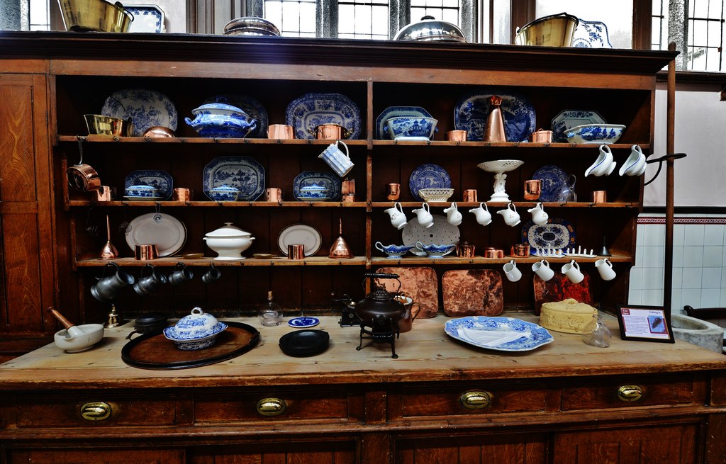 Kitchen dresser with a variety of mugs and other cooking equipment on